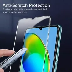 A smartphone screen protector being placed over a phone while a utility knife is held near the screen, demonstrating its anti-scratch protection against sharp objects