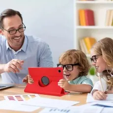 Red 360° rotating leather case on a Samsung Galaxy Tab A9 Plus 11-Inch 2023, set up in stand mode on a desk with people working together and bookshelves in the background