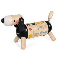 A young girl looks at the camera while holding a wooden toy dog with a segmented body