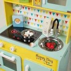 A close-up of the Janod toy kitchen's countertop with toy mushrooms in a pan on the stove and peppers in the sink.