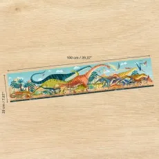 A wide, panoramic dinosaur puzzle on a wooden surface, showing its length of 100 cm and height of 20 cm