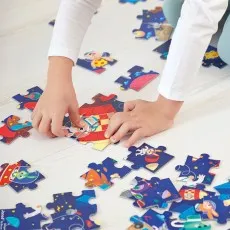 A child's hands putting together a colorful Janod puzzle of rabbits in space on a wooden floor.