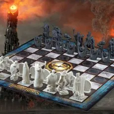 A dramatic, full view of The Lord of the Rings chess set on a board with the Eye of Sauron and Barad-dûr in the background