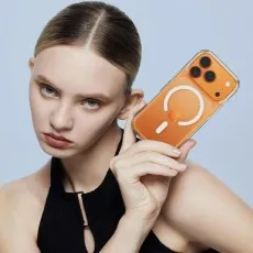 Model holding an orange iPhone in a clear case, prominently displaying the white MagSafe ring alignment..
