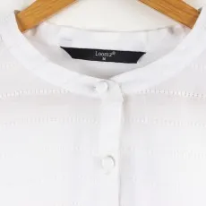 Close-up of a white boho blouse neckline featuring a mandarin collar and delicate button-down front.