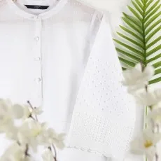 Close-up of white boho blouse showing intricate eyelet embroidery on bell sleeves and button-up front.